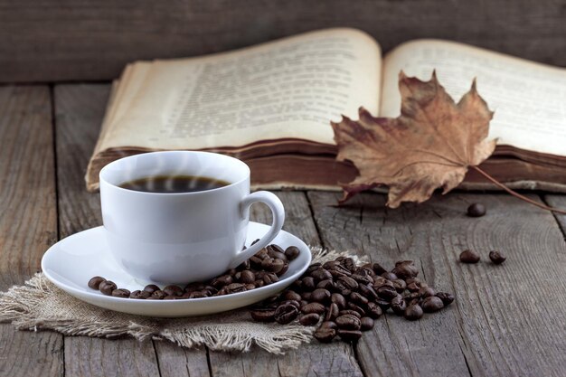 Tasse Kaffee und altes Buch mit Herbstblatt