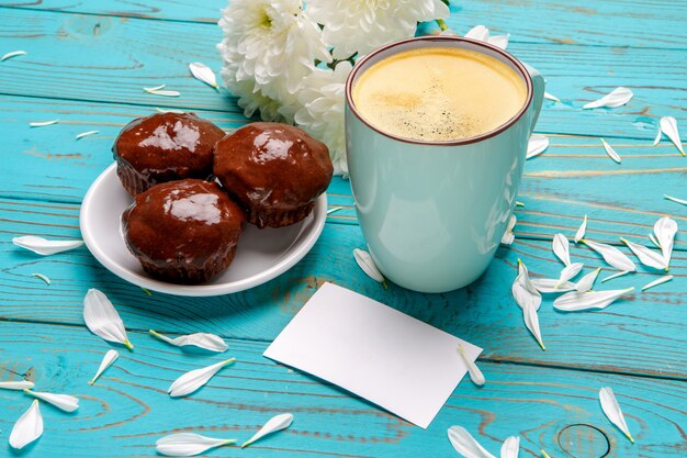 Tasse Kaffee und Blumen auf hellem Holztisch