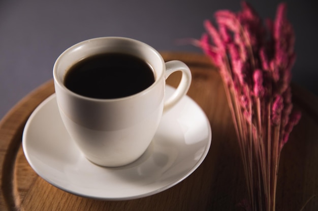 Tasse Kaffee und Blumen auf Holzbrett