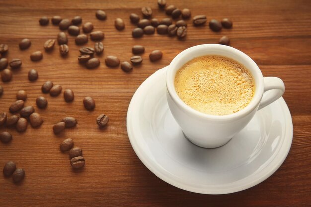 Tasse Kaffee und Bohnen auf hölzernem Hintergrund