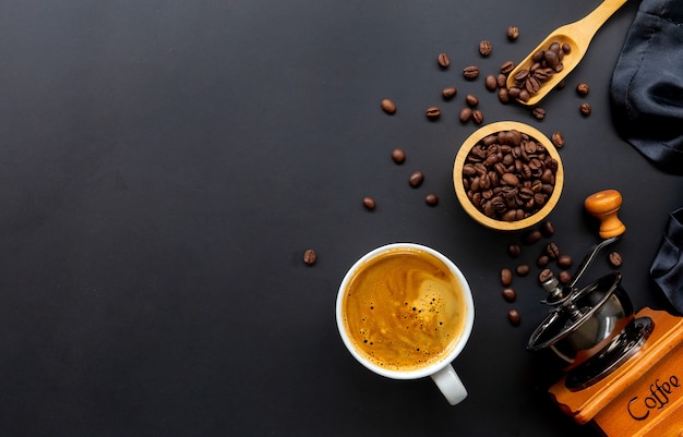 Tasse Kaffee und Bohnen auf schwarzem Holztisch