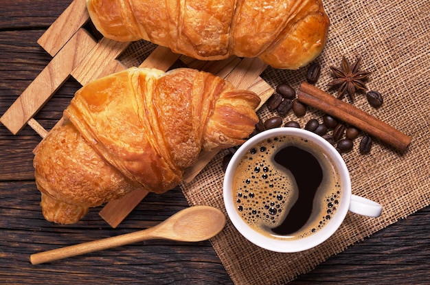 Tasse Kaffee und Croissants auf Draufsicht des rustikalen Holztischs