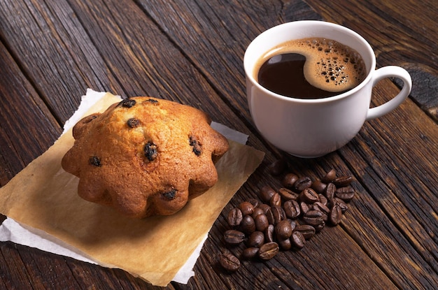 Tasse Kaffee und Cupcake mit Rosinen auf dunklem Holztisch