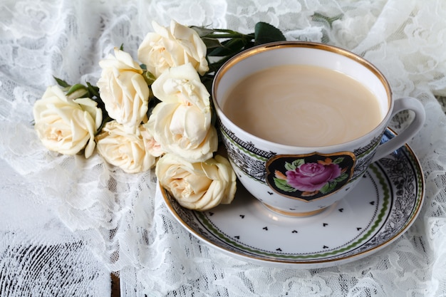 Tasse Kaffee und ein Strauß weißer Rosen