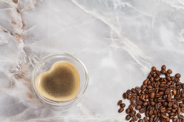 Tasse Kaffee und geröstete Kaffeebohnen auf dem Küchenschreibtisch