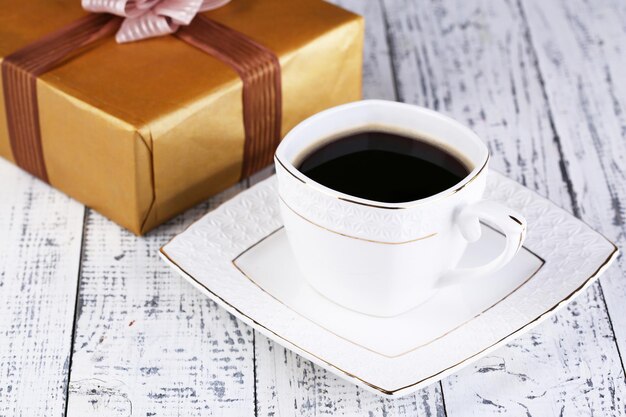 Tasse Kaffee und Geschenk auf Holztisch Nahaufnahme