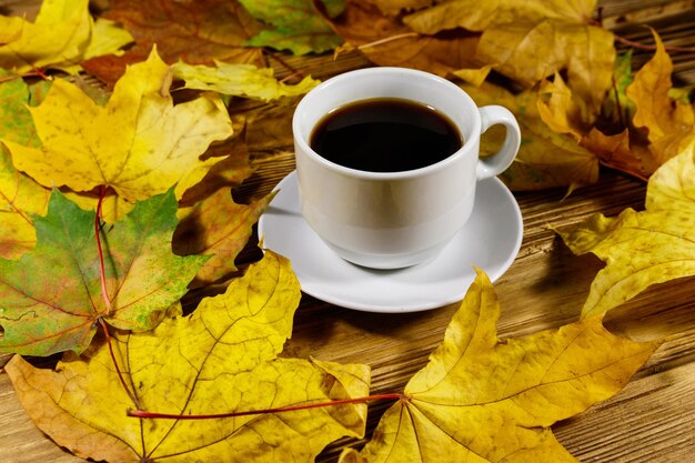 Tasse Kaffee und Herbstahornblätter auf Holztisch Herbstkonzept