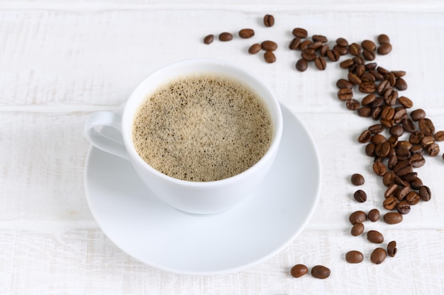 Foto tasse kaffee und kaffeebohnen auf draufsicht des weißen holztischs