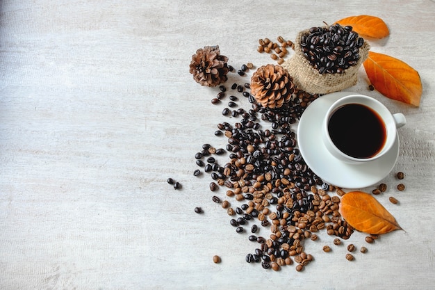 Tasse Kaffee und Kaffeebohnen auf einem weißen hölzernen Hintergrund platzieren