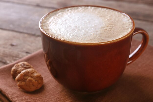 Tasse Kaffee und Kekse auf Serviette auf Holzhintergrund