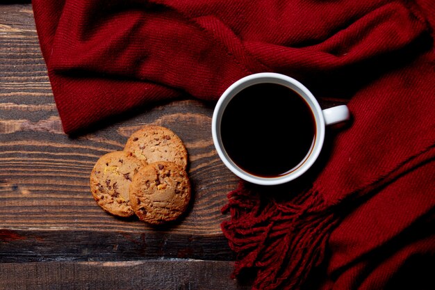 Tasse Kaffee und Kekse mit Schal auf Holztisch