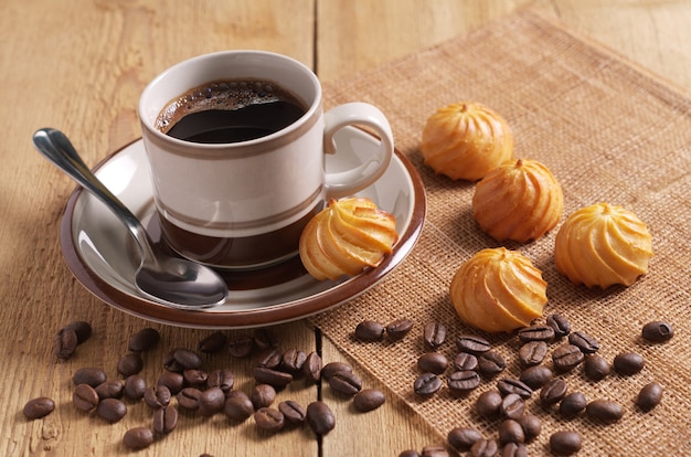 Tasse Kaffee und kleine Vanillepuddingkuchen auf Holztisch