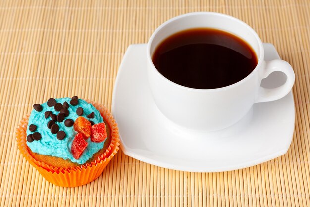 Tasse Kaffee und kleiner Kuchen mit Draufsicht der Sahne- und Schokoladentropfen