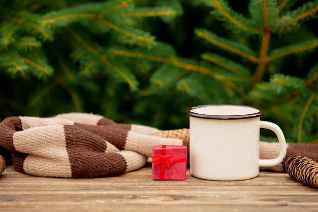 Tasse Kaffee und kleines Geschenk auf Holztisch mit Fichtenzweigen auf Hintergrund