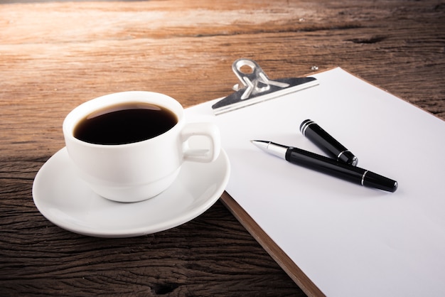 Foto tasse kaffee und klemmbrett mit leerseite und stift auf holztisch