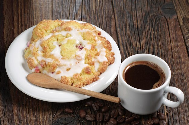 Tasse Kaffee und Kuchen mit Kirsche auf altem Holztisch