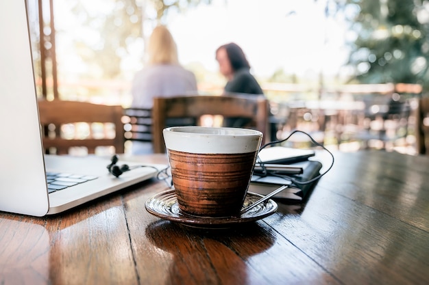 Tasse Kaffee und Laptop auf Holztisch im Café.