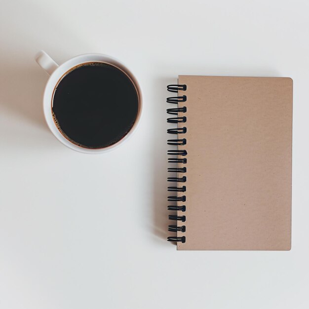 Tasse Kaffee und Notebook auf dem Tisch für minimalistische Foto-Branding