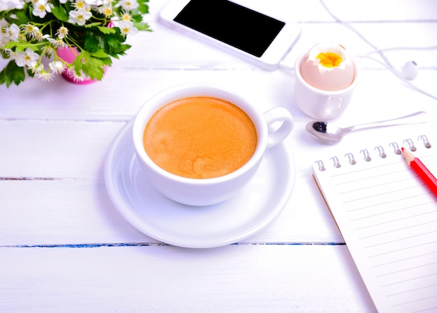 Tasse Kaffee und Notizbuch mit einem roten Bleistift