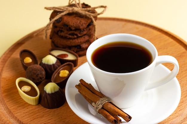 Tasse Kaffee und Pralinen auf einem Holztablett