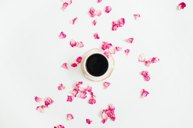 Tasse Kaffee und rosa Rosenblätter auf Weiß