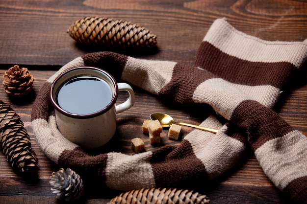 Tasse Kaffee und Schal auf Holztisch