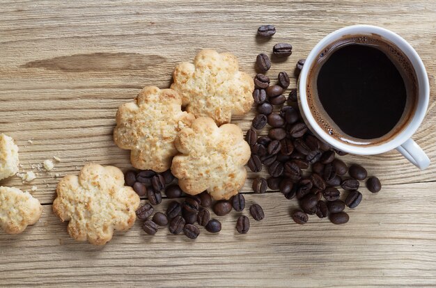 Tasse Kaffee und Shortbread mit Kokosnusschips auf altem Holz, Draufsicht