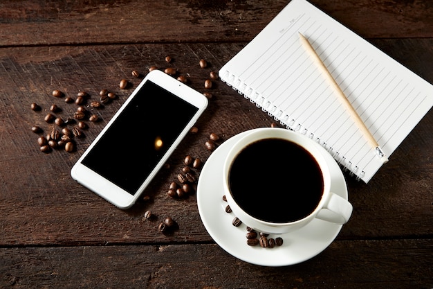 Tasse Kaffee und Smartphone auf dem Holz