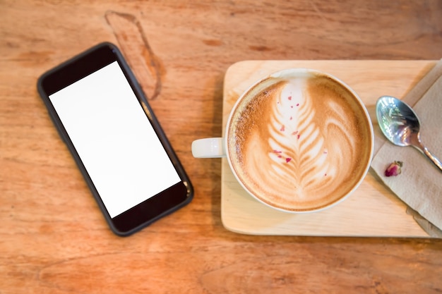 Tasse Kaffee und Smartphone auf Holztisch