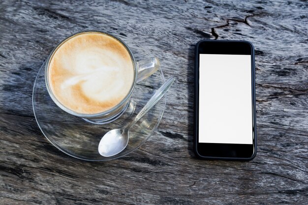 Tasse Kaffee und Smartphone auf Holztisch