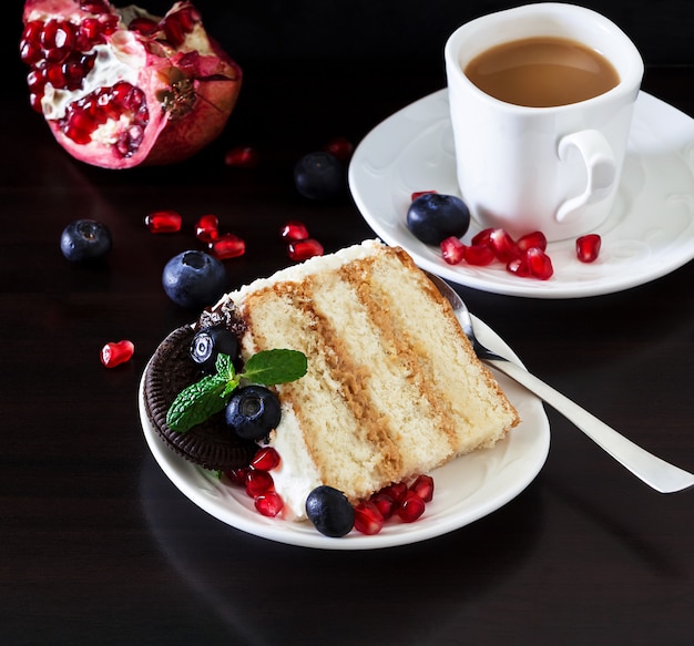 Tasse Kaffee und Stück Schichtkuchen mit frischen Blaubeeren, Frischkäse und Schokoladenkeksen. Dunkler hölzerner Hintergrund. Romantisches Valentinstagskonzept. Speicherplatz kopieren. Horizontales Banner