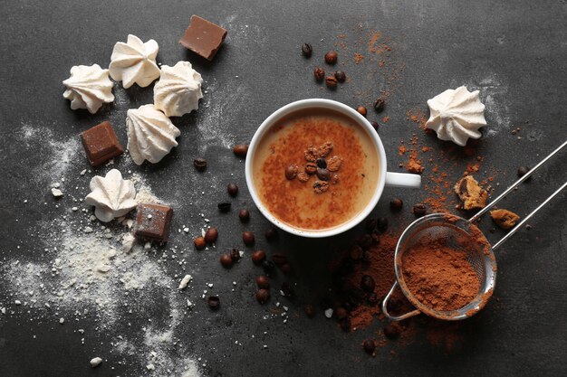 Tasse Kaffee und Süßigkeiten auf schwarzem Holzhintergrund