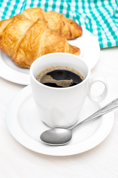 Tasse Kaffee und Teller mit Croissants auf dem weißen Tisch