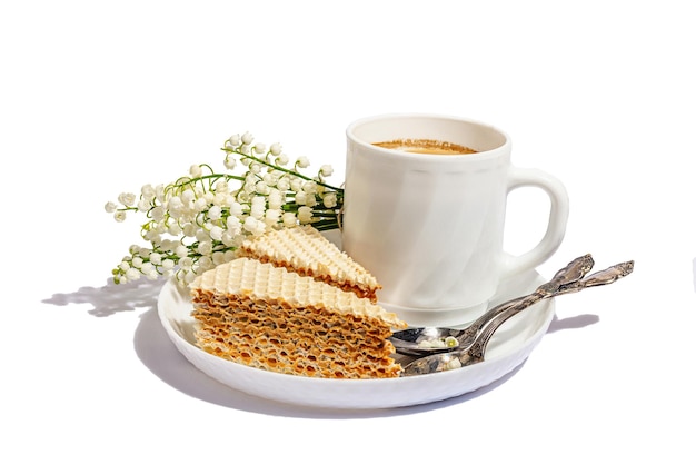 Tasse Kaffee und Waffelkuchen isoliert auf weißem Hintergrund Süßes Dessert mit Lily Valley Bouquet