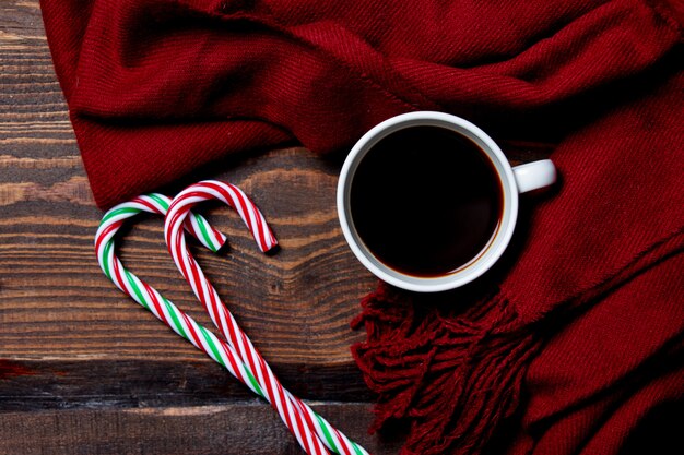 Tasse Kaffee und Zuckerstange mit Schal auf Holztisch