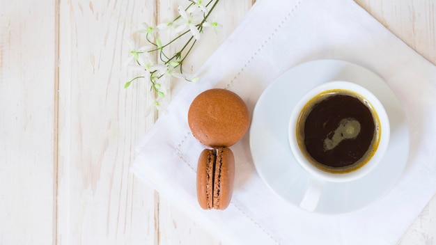 Tasse Kaffee und zwei Makronenkuchen auf weißem Holztisch