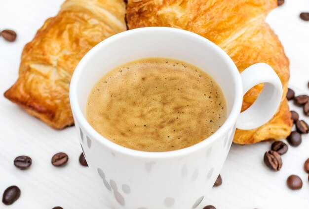 Tasse Kaffee zwei Croissants und Kaffeebohnen auf dem Tisch Draufsicht