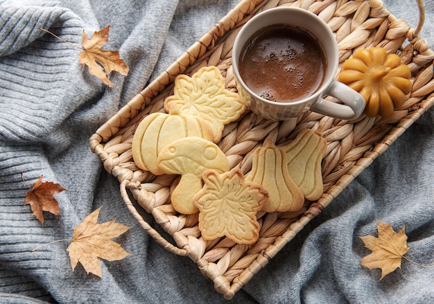 Tasse Kaffeeplätzchen auf gelben Blättern des Tabletts