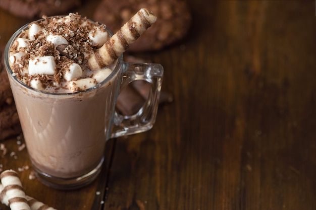 Tasse Kakao mit Marshmallows und Schokoladenkeksen auf dunklem Holz