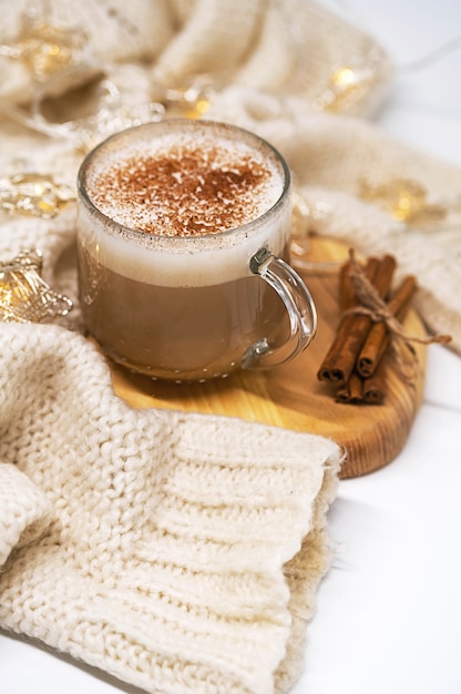 Tasse Latte Kaffee mit zimtweißem Pullover und Weihnachtsgirlandenlichtern