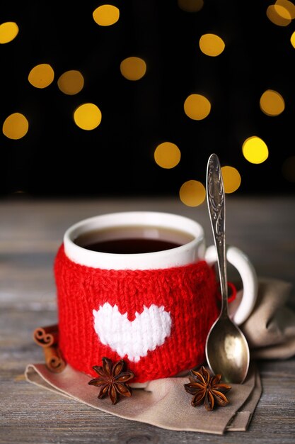 Tasse leckeren heißen Tee, auf Holztisch, auf glänzendem Hintergrund