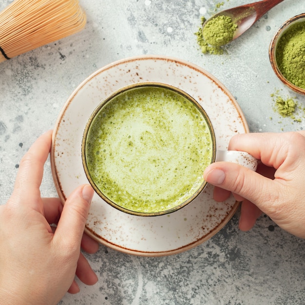 Tasse Matcha-Grüntee in Frauenhänden.