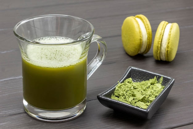 Tasse Matcha-Grüntee Schüssel mit Matcha-Pulver und zwei Makkaroni-Kuchen