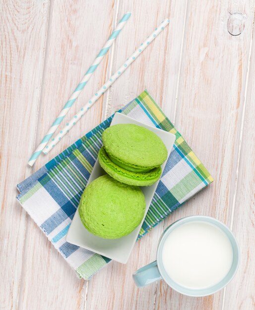 Tasse Milch und Macarons auf weißem Holztisch