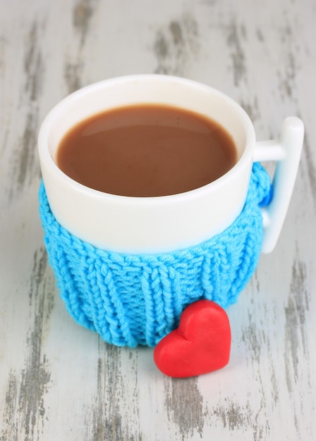 Tasse mit gestricktem Ding darauf auf Holztisch aus nächster Nähe