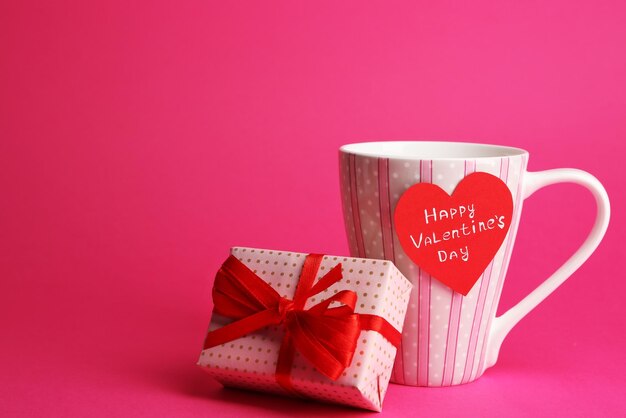 Tasse mit grußkarte und geschenkbox zum valentinstag auf rosa hintergrund