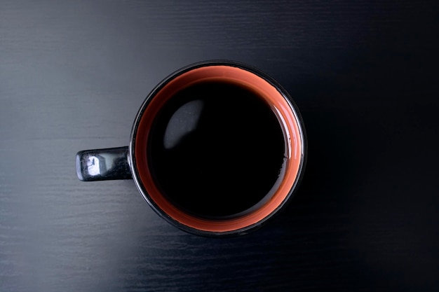 Tasse mit Kaffee auf schwarzem Holztisch