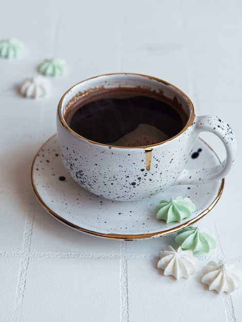 Tasse mit Kaffee und kleinen Baisers auf einer gefliesten Oberfläche