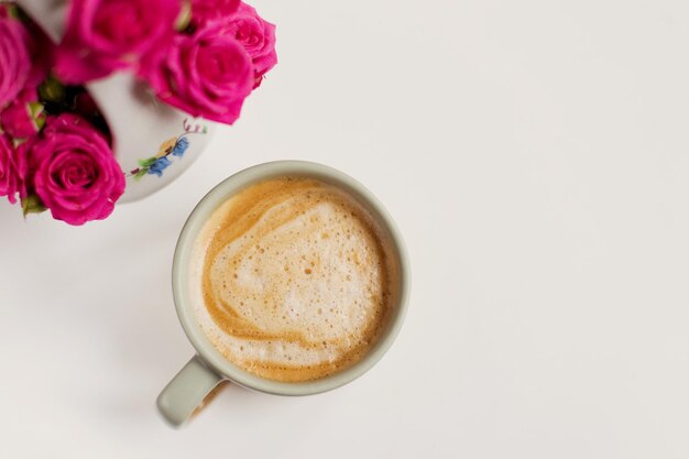 Tasse mit Kaffee und rosa Blumen