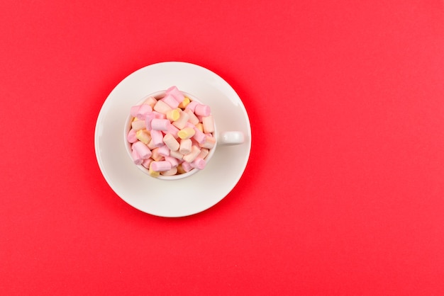 Tasse mit Marshmallow auf einem roten.